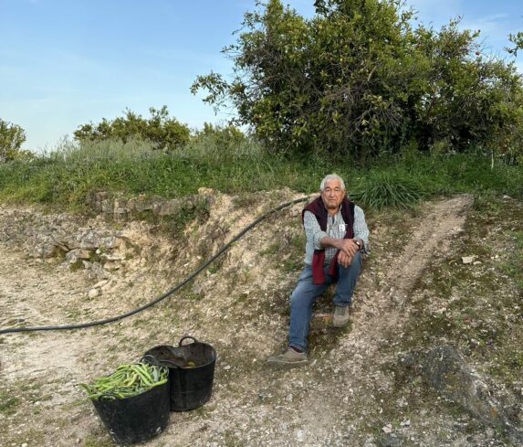 Eduardo resting by the orchard with buckets